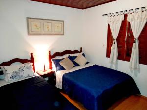 1 dormitorio con 2 camas con sábanas azules y ventana en Pousada Monte Suiço, en Campos do Jordão