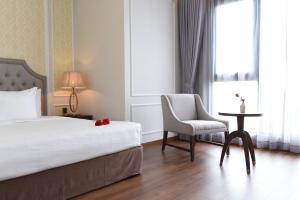 een slaapkamer met een bed, een stoel en een tafel bij Phu Cuong Hotel Ca Mau in Cà Mau