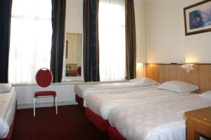 a hotel room with two beds and a red chair at Hotel de Westertoren in Amsterdam