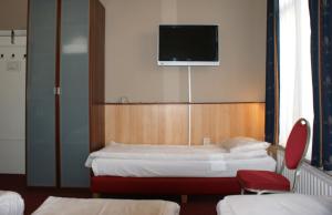 a room with two beds and a tv on the wall at Hotel de Westertoren in Amsterdam