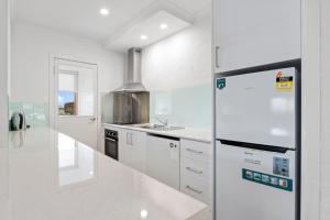
a kitchen with white cabinets and white appliances at Hideaway on George in Launceston
