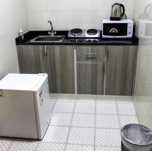 a small kitchen with a sink and a microwave at Barka Hotel Apartment in Samhān