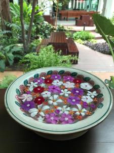 a bowl filled with flowers on top of a table at บ้านเวียงเหล็ก Baan Veanglhek Residence in Phra Nakhon Si Ayutthaya