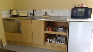 a kitchen with a sink and a microwave at The French Quarter accommodation in Katikati in Katikati