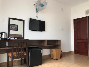 a room with a desk and a television on a wall at Hotel Hoàng Hưng Quy Nhơn in Quy Nhon