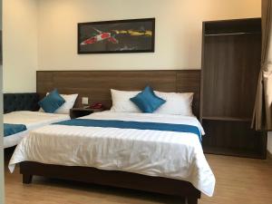 una camera con 2 letti con cuscini blu e bianchi di Hotel Hoàng Hưng Quy Nhơn a Quy Nhon