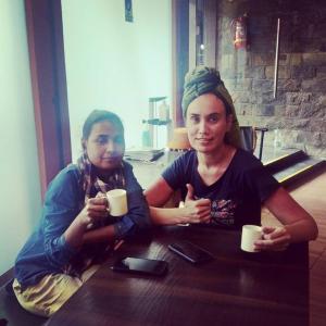 Dos mujeres sentadas en una mesa con tazas de café en Backpack Stay, en Bombay