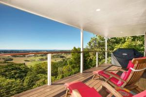 a deck with chairs and a view of the countryside at Byron's Secret in Coorabell Creek