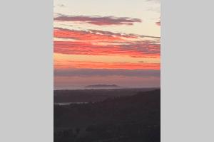 a sunset in the sky with a mountain in the distance at Byron's Secret in Coorabell Creek