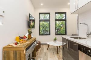 a kitchen with white walls and windows and a counter at Lofts du Parc LaHaie in Montréal