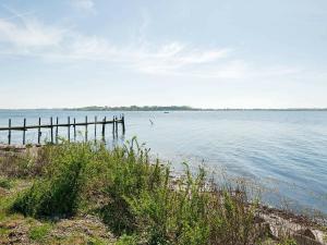 a large body of water with a wooden pier at 4 person holiday home in Gr sten in Gråsten