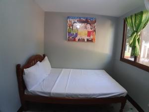 Cama pequeña en habitación con ventana en OYO 671 Natua's Cabin, en Puerto Princesa City