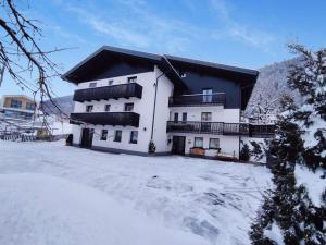 a white building with a black roof in the snow at Residence Karpoforus in Laces