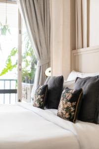 - un lit blanc avec des oreillers noirs et une fenêtre dans l'établissement B House Samui, à Bangrak Beach