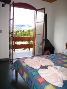 a bedroom with a bed and a sliding glass door at Pousada Cachyto de Cielo in Campos do Jordão