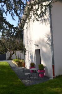 um pátio com duas cadeiras e uma mesa num quintal em Demeure & Dépendance - Chambres d'hôtes depuis 2012 em Tassin-la-Demi-Lune