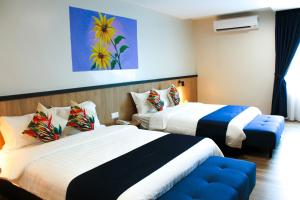 a hotel room with two beds and a couch at Savana Hotel & Serviced Apartments in Kuala Perlis