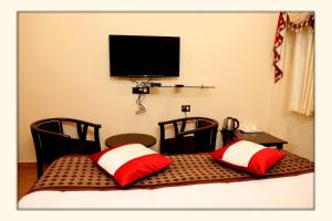 a room with two chairs and a television on the wall at The Ranikhet Continental in Rānīkhet