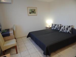 a bedroom with a black bed and a chair at Újsziget Vendégház in Sárvár