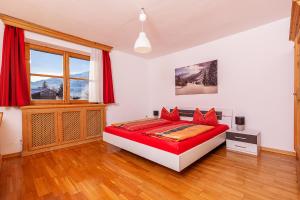 une chambre avec un lit avec des oreillers rouges dans l'établissement Ferienresidenz Florian, à St. Johann in Tirol