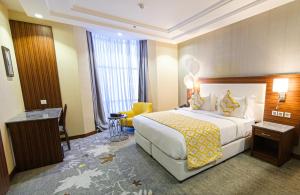 um quarto de hotel com uma cama grande e uma cadeira amarela em Taj Al Worood Hotel em Jeddah