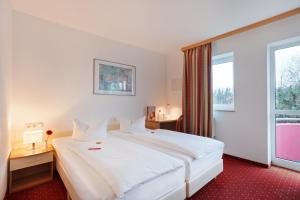 ein Hotelzimmer mit einem großen weißen Bett und einem Fenster in der Unterkunft Andante Hotel Erding in Erding