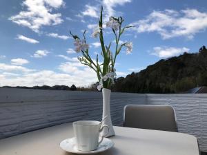 eine Vase mit weißen Blumen auf einem Tisch mit einer Tasse in der Unterkunft Kamogawa - House - Vacation STAY 9977 in Kamogawa