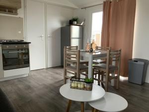 Chalet Zonnig Zeeland في أوستكابيلي: مطبخ مع طاولة وكراسي وثلاجة