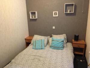 a bedroom with a bed with two blue pillows at Knus appartement met zijdelings zeezicht in Ostend