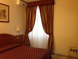 een slaapkamer met een bed en een raam met gordijnen bij Hotel Chicago in Rome