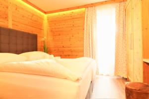 a bedroom with a white bed and a window at Alpin & See Resort - Pinzgau Holidays in Zell am See