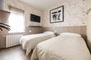sypialnia z dwoma łóżkami i telewizorem na ścianie w obiekcie Boutique House Alzira w mieście Alzira
