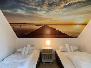 two beds in a room with a painting of a pier at My Brand Boardinghouse Hamburg Volksdorf in Hamburg