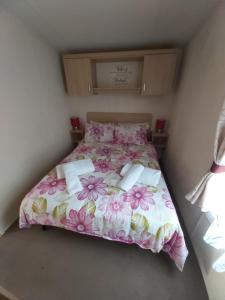 
a bed with a white comforter and pillows on it at Caravan on the Devon\Cornwall border in Stratton

