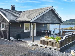 una casa negra con terraza y mesa en 8 person holiday home in TORVIKBUKT, en Torvikbukt