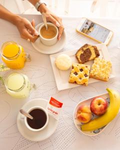 a table with breakfast foods and coffee and a tablet at Hotel Ramos Mejía in Mar del Plata