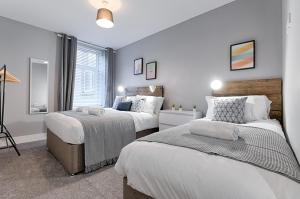 a bedroom with two beds and a window at Murray Nest #2 - TV in Every Bedroom! in Llanelli