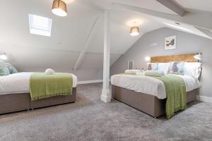 2 Betten in einem Schlafzimmer im Dachgeschoss mit weißen Wänden in der Unterkunft Murrays Nest #3 - TV in Every Bedroom! in Llanelli