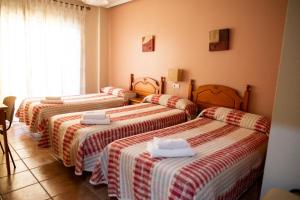 three beds in a room with red and white blankets at Pensión El Cordobés in Los Alcázares