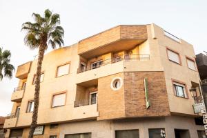 un edificio con una palmera delante de él en Pensión El Cordobés, en Los Alcázares