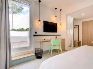 a bedroom with a bed and a desk and a window at ibis Styles Arcachon Gujan Mestras in Gujan-Mestras