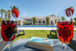 two wine glasses sitting on a table with a book at Villa Koster by Algarve Vacation in Carvoeiro