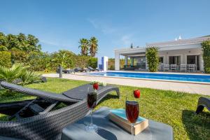 a villa with a swimming pool and a table with wine glasses at Villa Koster by Algarve Vacation in Carvoeiro