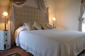 een slaapkamer met een groot wit bed met 2 lampen bij Villa Le Ginestre in Cortona