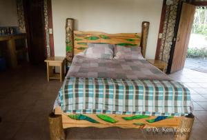 a wooden bed with a checkered blanket on it at Cascata Del Bosco Cabinas in San Vito