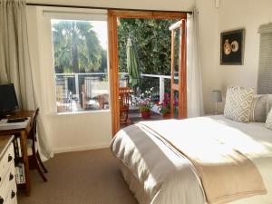 a bedroom with a bed and a large window at Oceangolf Guest House in Noordhoek