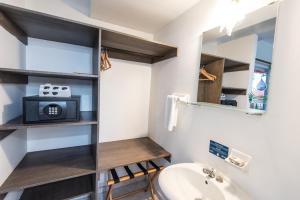 ein Badezimmer mit einem Waschbecken und einem TV auf einem Regal in der Unterkunft Sunset Hotel in San Andrés