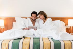 un uomo e una donna a letto con un tablet di Hotel Luna a Bibione