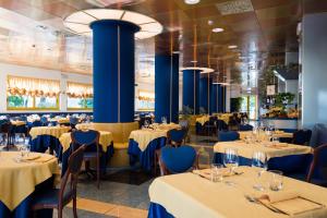 un restaurante con mesas, sillas y columnas azules en Hotel Luna en Bibione