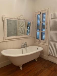 a white bath tub in a bathroom with two windows at Chez Louise in Albi